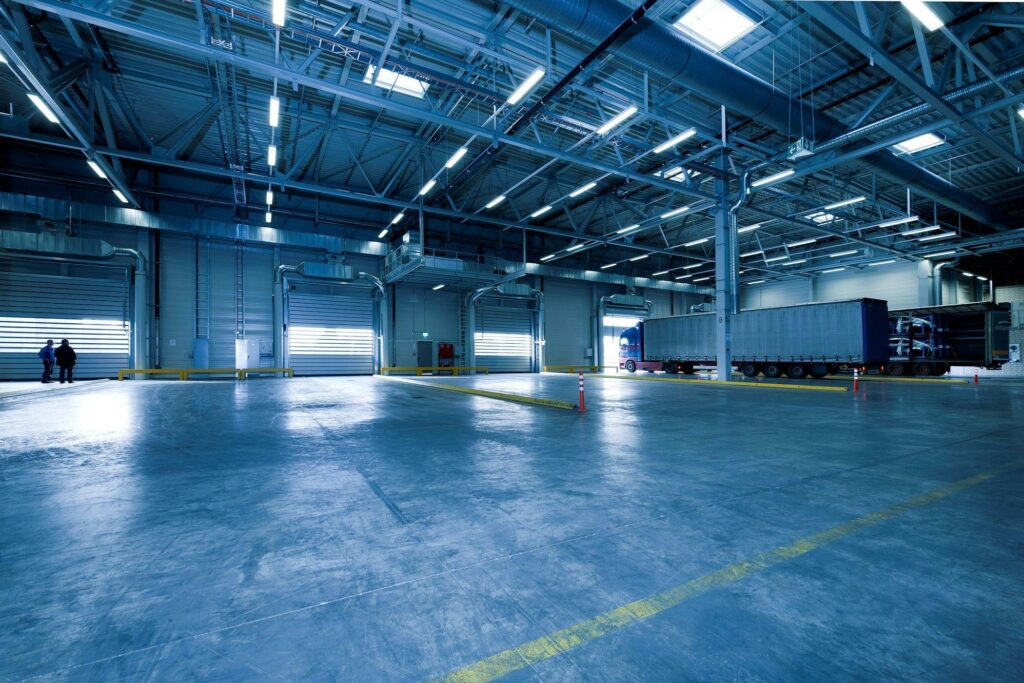 pexels-photo-257636-257636 Wide view of an empty modern warehouse with industrial lighting and trucks.